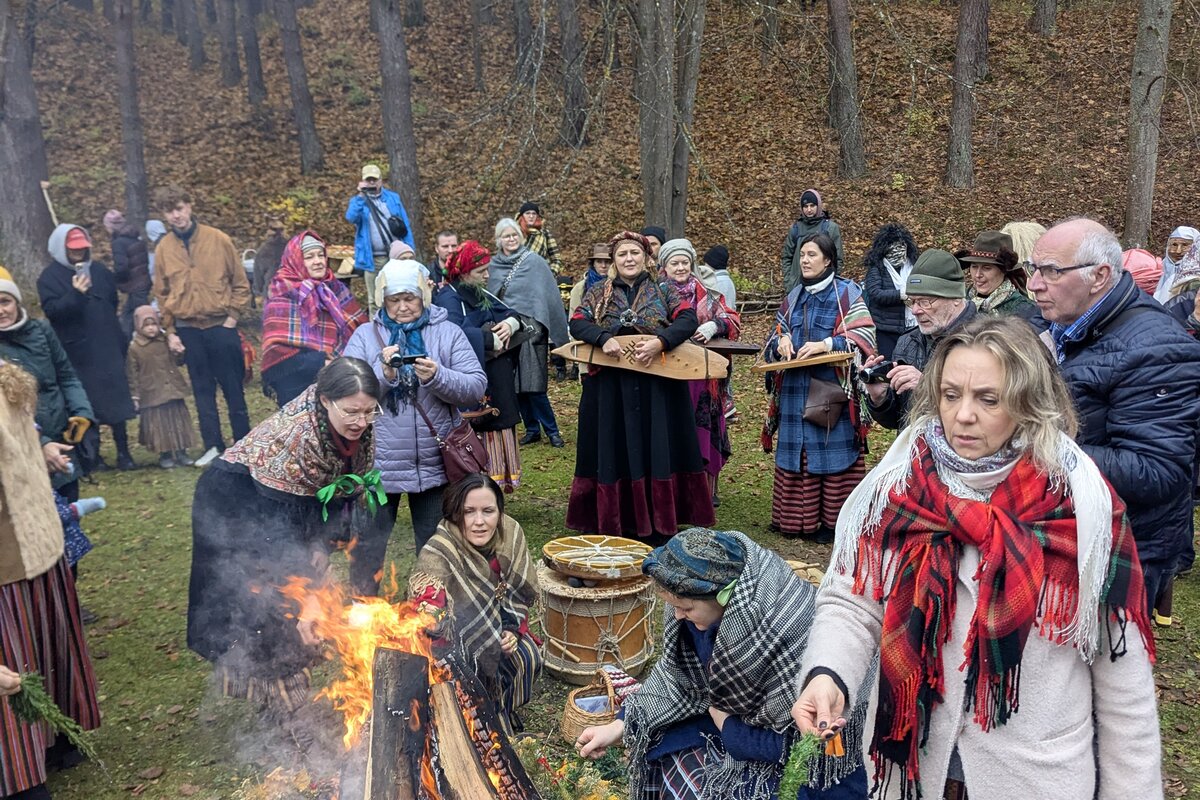 Apmeklētāji tautas tērpos pie Mārtiņdienas ugunskura Etnogrāfiskajā brīvdabas muzejā, Rīgā.