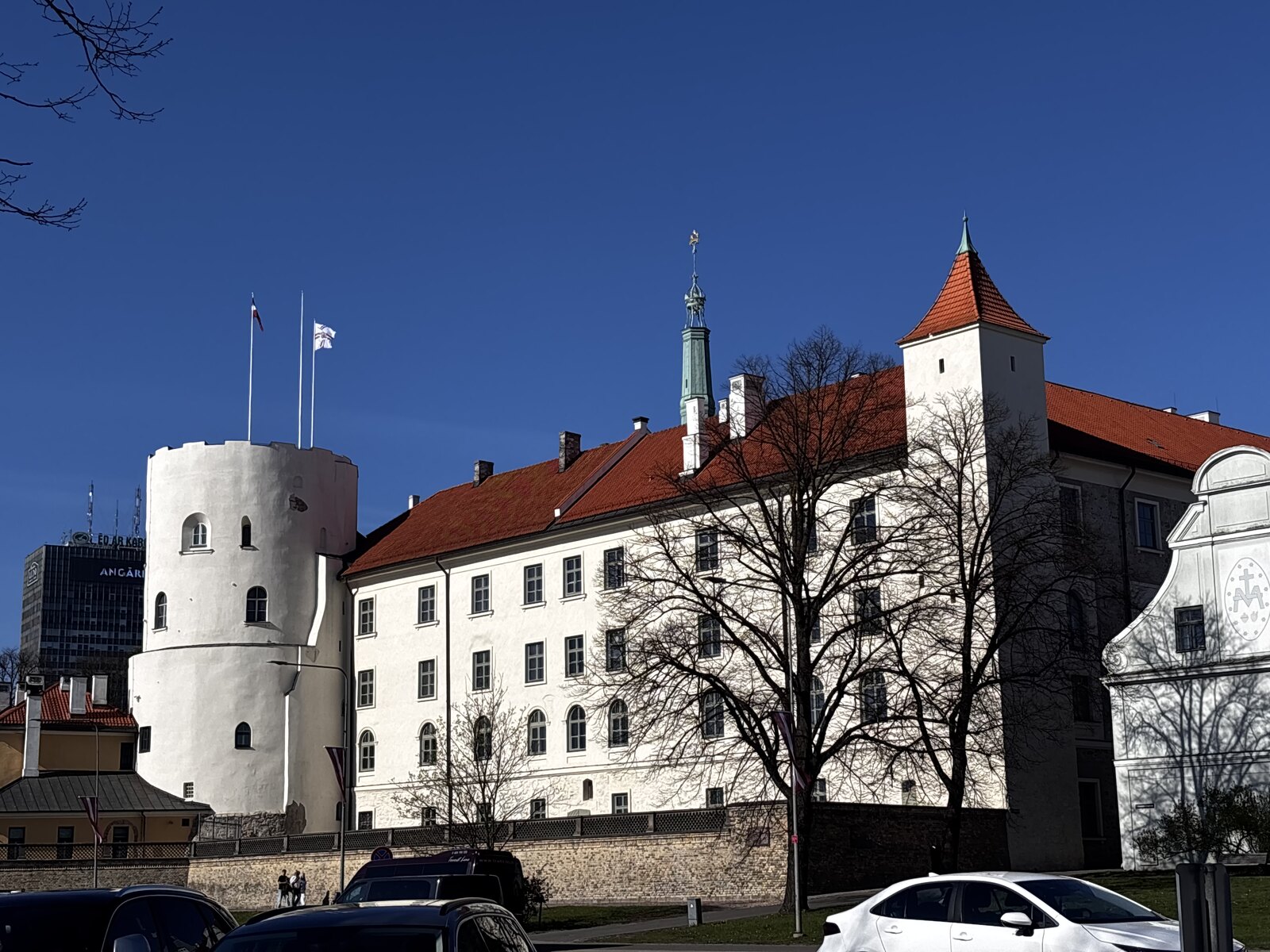 Rīgas pils ar baltām sienām, sarkano jumtu un apaļo Svētā Gara torni Rīgā, Latvija.