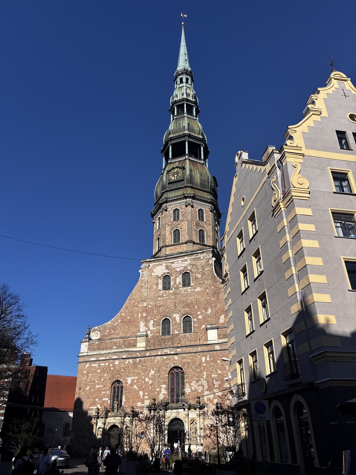 Sv. Pētera baznīca ar augsto zaļo torni pret zilām debesīm Rīgas Vecpilsētā, Latvijā.