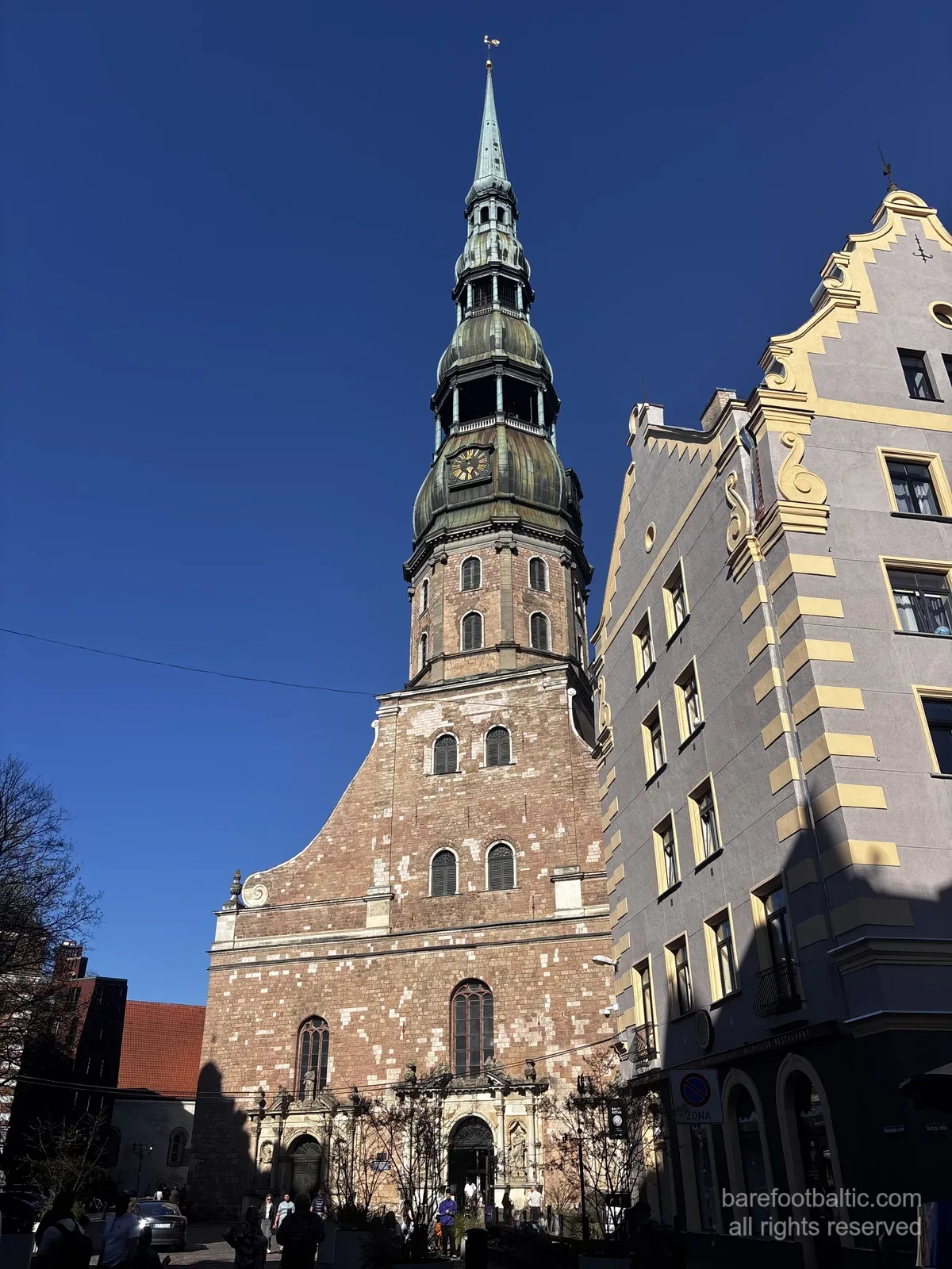 Sv. Pētera baznīca ar augsto zaļo torni pret zilām debesīm Rīgas Vecpilsētā, Latvijā.