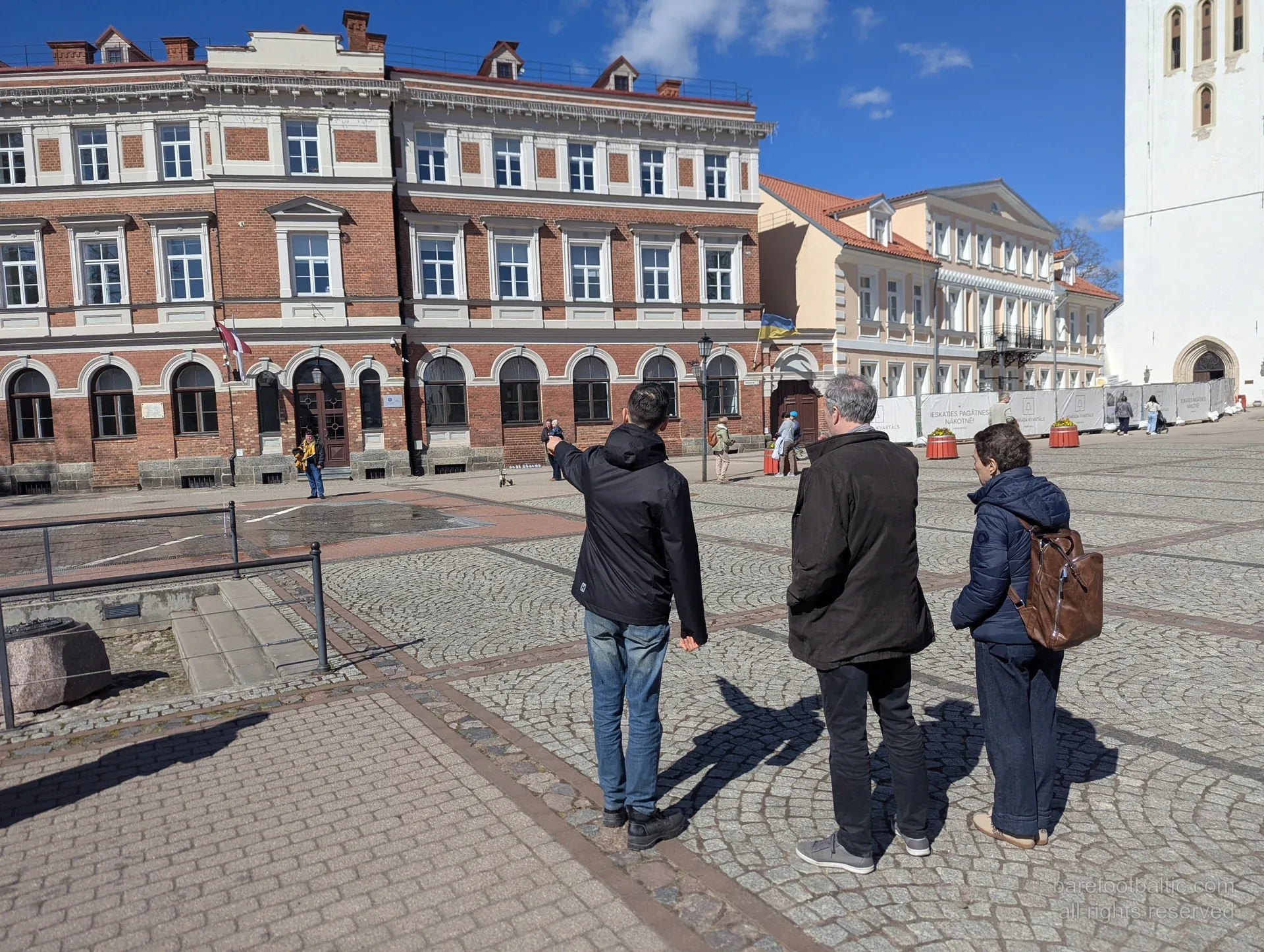 Cēsu vecpilsētas pastaiga, gide rāda vēsturisku ēku