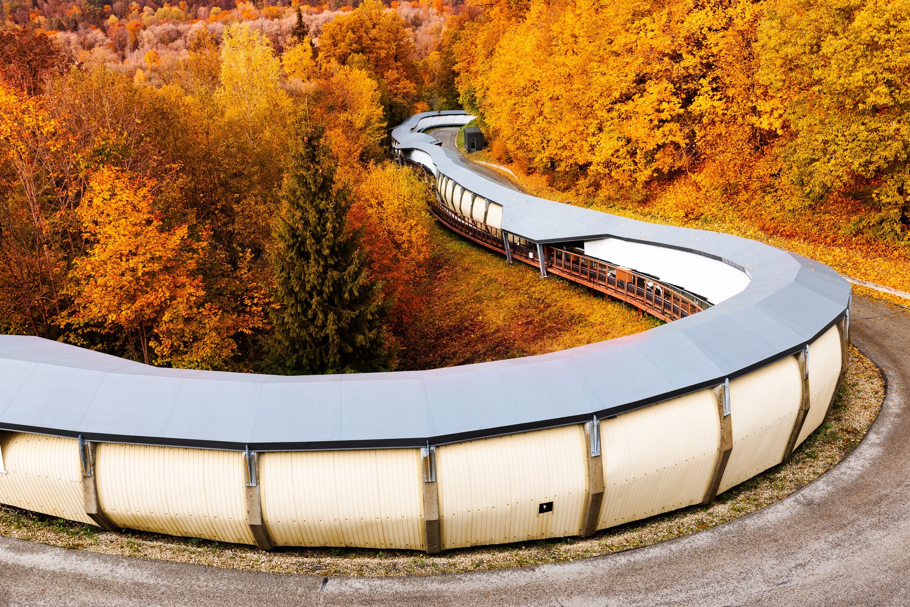 Siguldas olimpiskā bobsleja trase līkumo cauri rudens mežam
